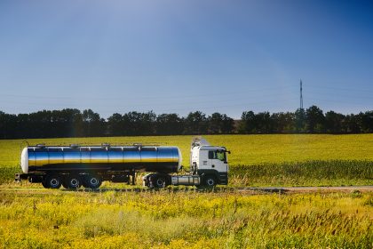 Milchsammelwagen auf Landstraße umgeben von Rapsfeldern
