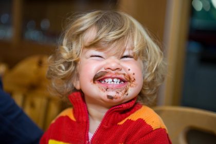 Blonder Junge mit lachendem Schokomund
