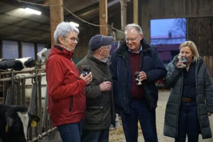 Stephan Weil, Milchbauer Helmut und seine Frau Birgit im Gespräch im Kuhstall.